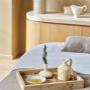 Massage bed at Aelia Spa with a wooden tray holding a small ceramic pitcher, bowl, and olive branch, set in a softly lit wellness suite.