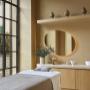 Calming spa treatment room with a massage bed, circular mirror, and built-in shelving decorated with natural elements at Aelia Spa.