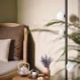 A cozy lounge chair with a tea set, candle, and lavender arrangement on a wooden side table.